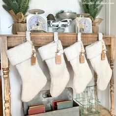 christmas stockings hanging from the mantle in front of a clock and other holiday decor items