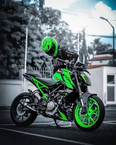 a man riding on the back of a green and black motorcycle in a parking lot