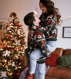 a woman holding a young boy in front of a christmas tree