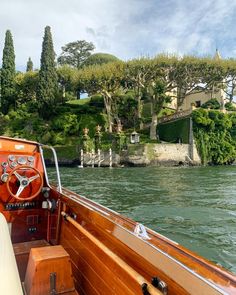 a boat traveling down a river next to a lush green hillside covered in lots of trees