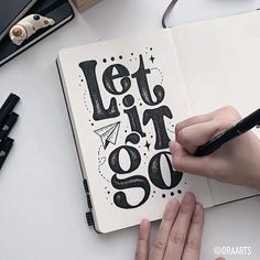 someone is writing on an open notebook with the words let it go written in black