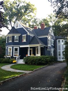 a large blue house with white trim on the front and side of it's windows