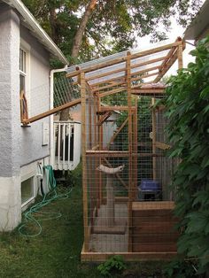 a bird cage sitting in the grass next to a house