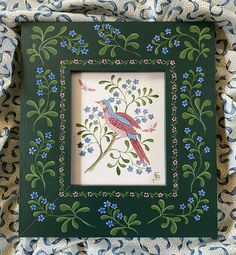 a green frame with blue flowers and a bird on it