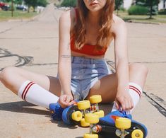 a young woman sitting on the ground with her skateboard in front of her feet