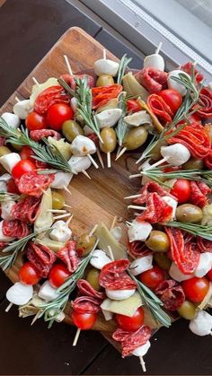 a wreath made out of vegetables and meats on a cutting board next to a window