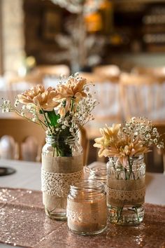 two mason jars filled with flowers on top of a table