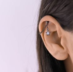 a woman's ear is shown with two stars on the chain attached to it