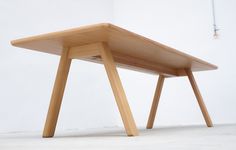 a wooden table sitting on top of a white floor next to a light colored wall