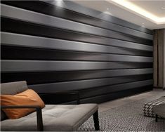 a modern living room with black and white stripes on the wall, gray chair and ottoman