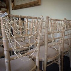 rows of chairs with pearls attached to them in a room next to a framed painting