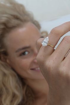 a woman wearing a ring with a pear shaped diamond on it's middle finger