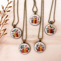 four necklaces with different designs on them hanging from a wooden table next to a plant