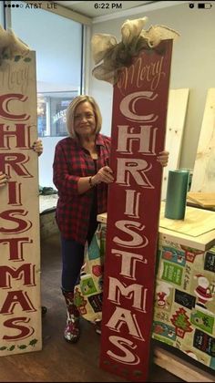 a woman standing next to two wooden christmas signs