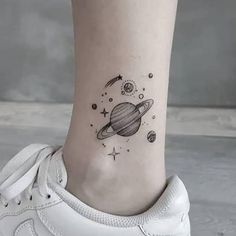 a small saturn tattoo on the ankle