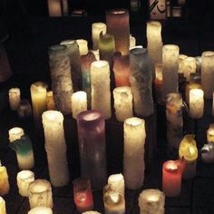 many lit candles are arranged in rows on the floor