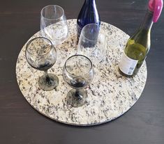 three wine glasses and two bottles on a marble tray