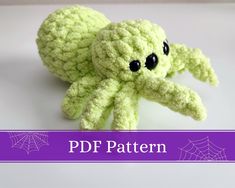 a crocheted green stuffed animal sitting on top of a white table next to a purple banner