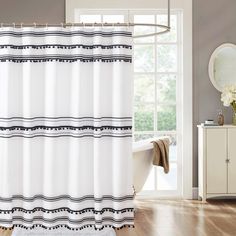 a white shower curtain with black and white stripes on it in a bathroom next to a window