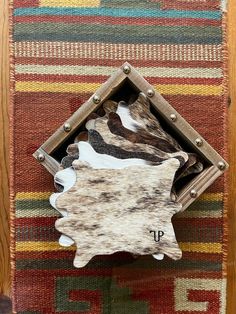 Our Branded Cowhide Coasters Set is a very popular and useful accent in ranch and western style homes and bars. This 6-piece coaster set comes in a handmade reclaimed barn wood box lined with coordinating leather and adorned with a western floral embossed leather belt and a nickel embossed belt buckle. Branded Cowhide Coasters Details: Each cowhide piece is die-cut in the shape of a mini cowhide rug. Customized with your personal family or ranch brand. Each coaster is different and made from all Branded Cowhide, Western House Decor, Western House Ideas, Western Style Bedroom, Cowhide Coasters, Horse Room Decor, Cowhide Decor, Western Games, Horse Room