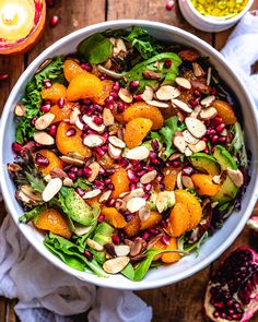 a salad with oranges, almonds and spinach in a white bowl on a wooden table