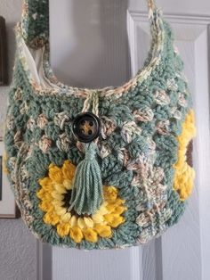 a crocheted purse hanging from a hook on a door handle with a button in the center