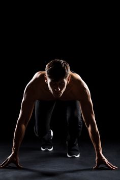 a man doing push ups in the dark with his hands behind his head and feet