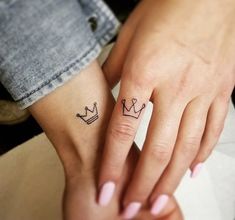 two people with matching tattoos on their hands, one is holding the other's hand