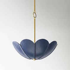 a blue flower hanging from a gold colored metal hook on a white wall and ceiling