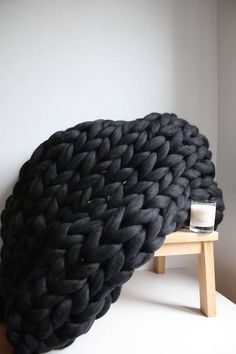 a large black blanket sitting on top of a wooden stool next to a white wall