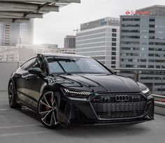 an audi sports car parked in front of some tall buildings