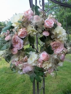 a bunch of flowers that are in a vase on a stand with grass and trees behind it