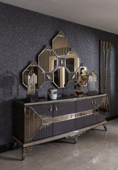 a black and gold sideboard with mirrors on it's sides, in front of a gray wall