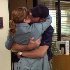 two people hugging each other in an office