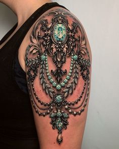 a woman's arm with an ornate tattoo design on the left side of her shoulder