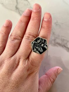 a person's hand with a ring on it that has black and white designs