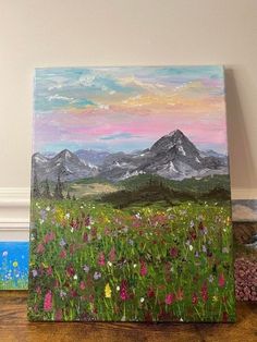 a painting of mountains and wildflowers on a wooden floor with flowers in the foreground