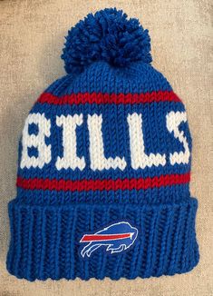 a knit beanie with the word bills written on it and a buffalo logo in red, white, and blue