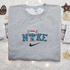 The Nike Christmas x Stitch Santa and Scrump Embroidered Sweatshirt is the perfect holiday attire for Disney lovers. This limited-edition sweatshirt showcases a delightful collaboration between Nike and the beloved characters Stitch, Santa, and Scrump. Crafted with premium quality fabric, it offers unparalleled comfort and durability. The intricate embroidery adds a festive touch, making it a standout piece for any Christmas party or gathering. With its versatile design, it can be effortlessly s Nike Cartoon, Disney Character Shirts, Nike Inspired, Best Family Gifts, Maroon Hoodie, Embroidered Shirts, Mike Wazowski, Heart Embroidery, Hoodie Material