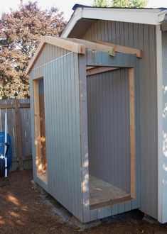 a small shed with the door open and some wood on the ground next to it