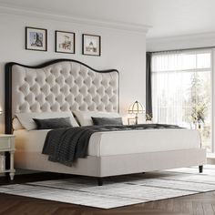 a white bed sitting in a bedroom on top of a hard wood floor next to a window