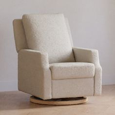 a white rocking chair sitting on top of a hard wood floor next to a wall