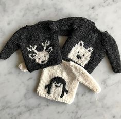 two knitted sweaters sitting on top of a marble counter