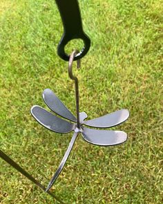 a metal dragonfly sitting on top of a lush green field