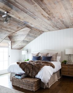 a bedroom with wood floors and white walls, has a large bed covered in fur