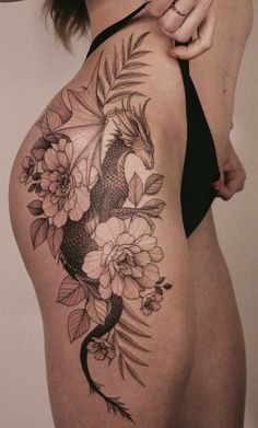 the back of a woman's thigh with flowers and a koi fish tattoo on it