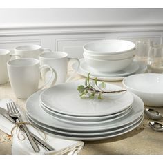 a table set with white dishes and silverware