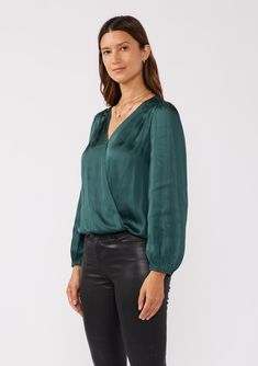 A soft and silky long sleeve holiday surplice blouse. Satin Relaxed fit Long sleeves Elastic wrist cuff Surplice v-neckline with hook & eye closure Elastic hemline Pleated shoulder details Women's holiday blouse Dry clean recommended or hand wash cold Step into the holiday season with elegance in our stunning surplice satin blouse, designed with a chic hook-and-eye closure, graceful long sleeves, and a comfortable elastic hemline. Whether you're headed to a family gathering or a corporate event, Blouse Satin, Holiday Blouses, Raglan Sleeve Top, High Rise Bootcut Jeans, Classic Blouses, Raglan Top, Color Block Cardigan, Chic Top, Satin Blouse