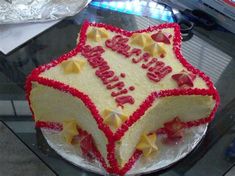 a birthday cake with red and white frosting on a glass table in front of a computer