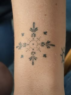 a snowflake tattoo on the arm of a woman's left arm and wrist